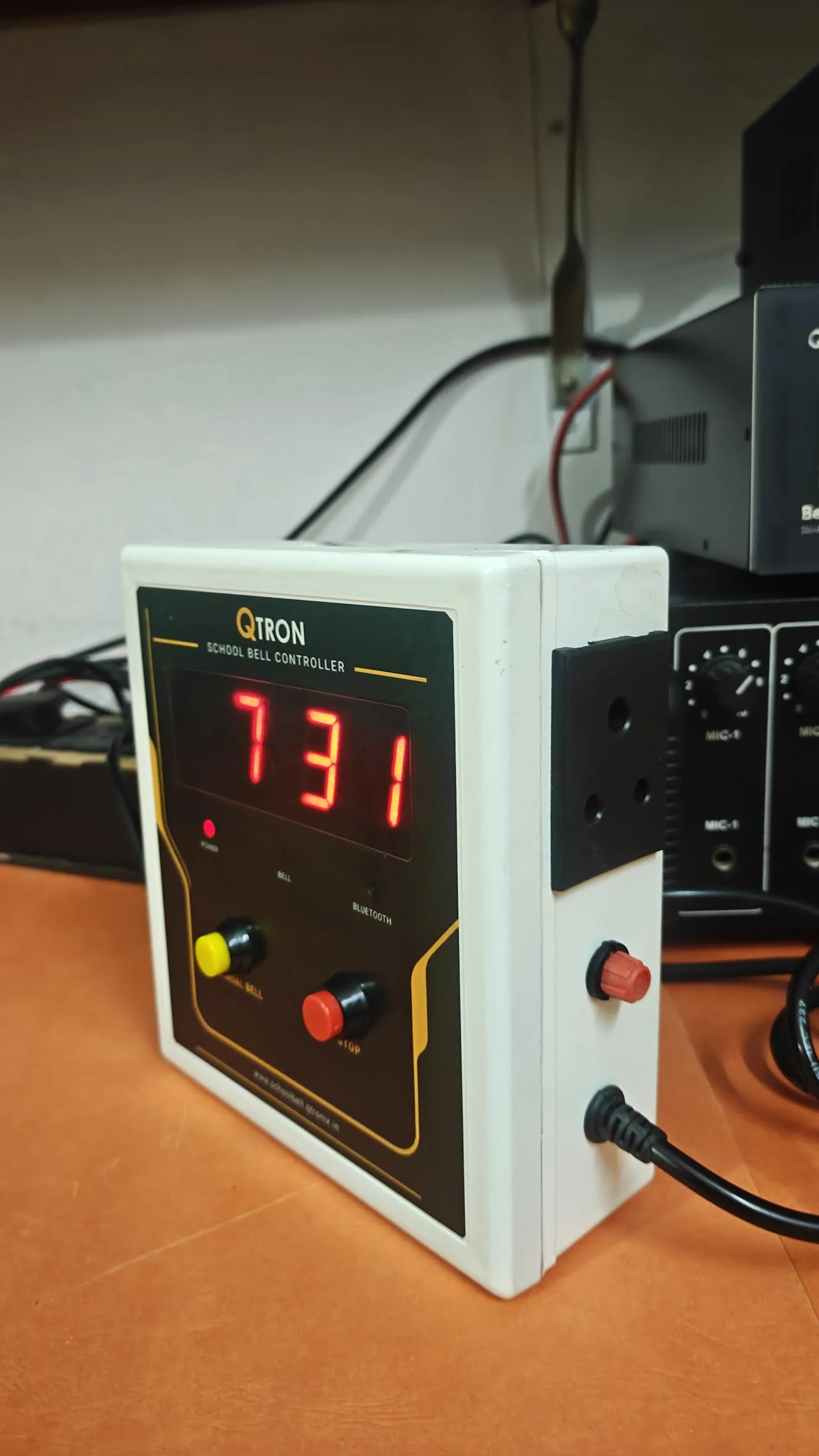 Actual side photograph showing the QTRON enclosure, manual and STOP buttons and cable